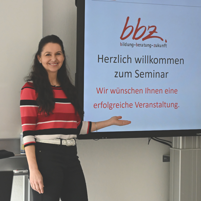 Frau präsentiert Willkommenstext für Seminar auf Bildschirm